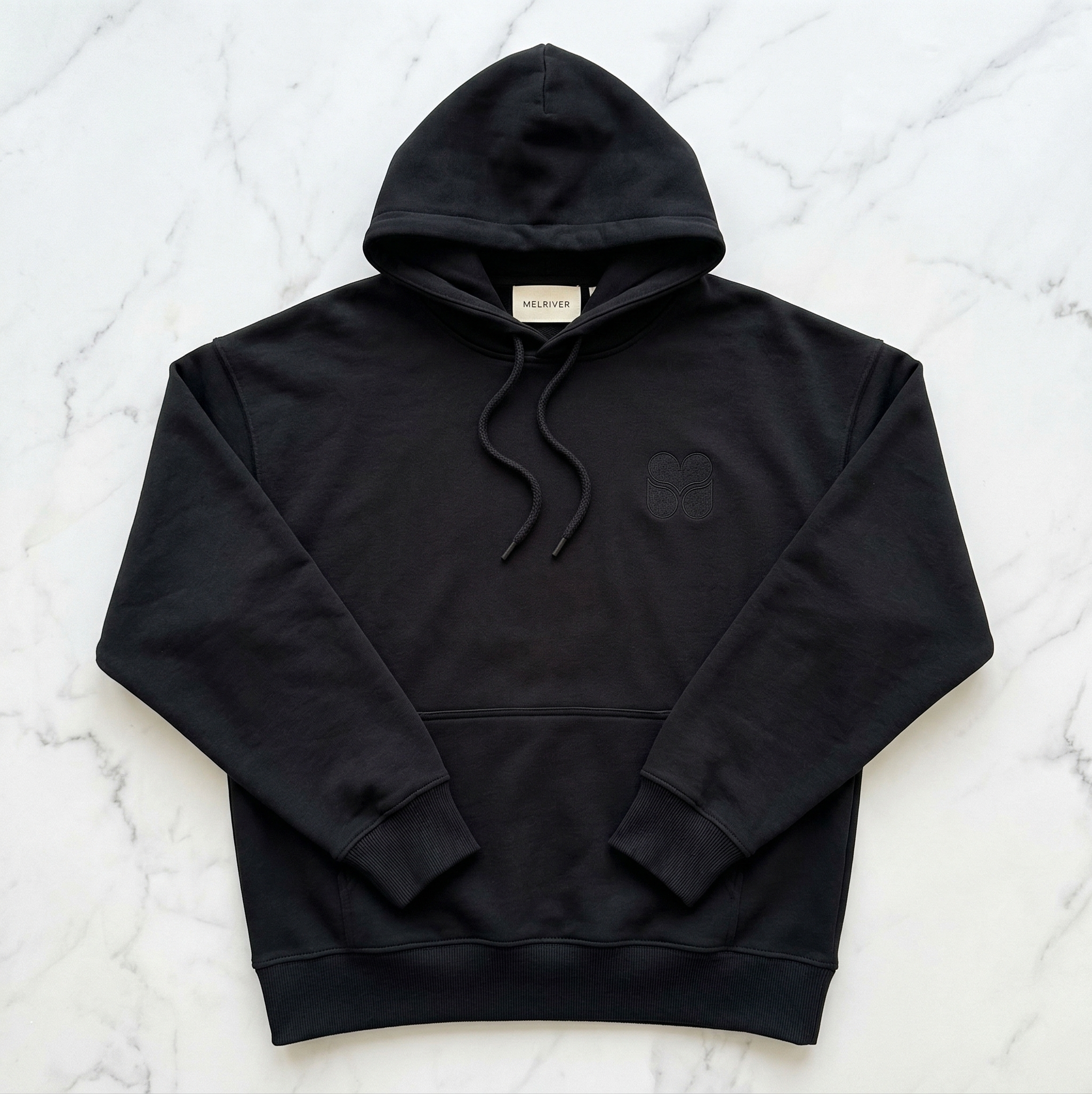 The Melriver Hoodie — Black heavyweight hoodie with embroidered Melriver icon, flat lay view